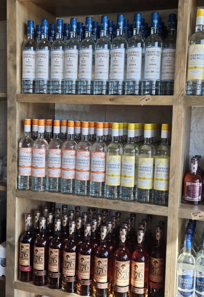 Texas Spirits: shelving filled with various bottles of dripping springs spirits.